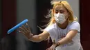 Seorang wanita yang mengenakan masker bermain dengan frisbee di Beijing, China, 13 April 2022. Shanghai bergerak untuk lebih melonggarkan lockdown di kota terbesar di China tersebut yang tampaknya terhenti. (AP Photo/Mark Schiefelbein)
