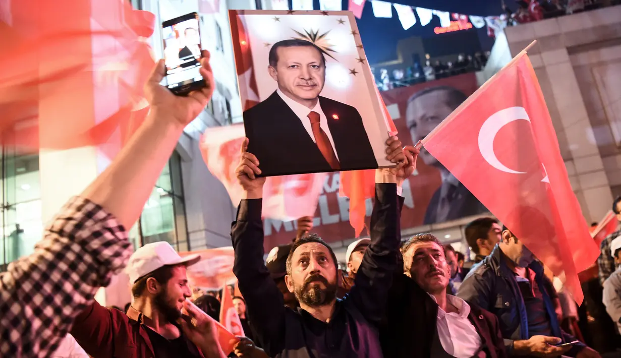 Seorang pria membawa poster Erdogan saat merayakan kemenangan dalam referendum di Istanbul, Turki (16/4). Pergantian sistem pemerintahan tersebut memungkinkan Erdogan memperoleh kekuasaan lebih luas dan masa jabatan lebih lama. (AFP Photo / Ozan Kose)