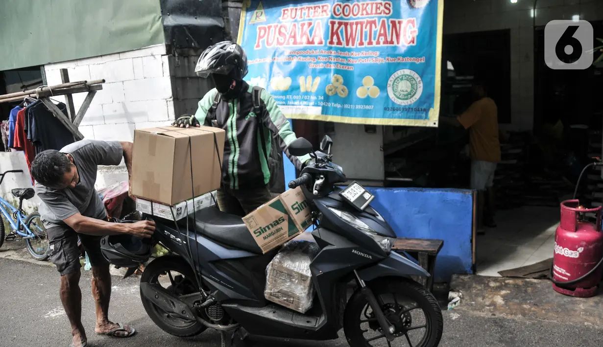 Pekerja menata produksi kue kering ke atas motor untuk diberikan kepada pelanggan di industri rumahan Pusaka Kwitang, Jakarta, Kamis (6/4/2023). (merdeka.com/Iqbal S Nugroho)