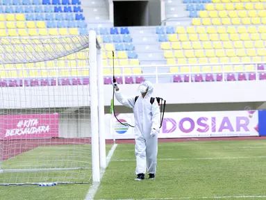 Petugas menyemprot jaring gawang dengan cairan disinfektan sebelum pertandingan antara Persikabo 1973 melawan Arema FC pada laga Piala Menpora di Stadion Manahan, Solo, Minggu (21/3/2021). (Bola.com/M Iqbal Ichsan)