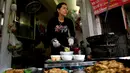 Penjual membuat kuliner cha ruoi di sebuah kios di Hanoi, Vietnam, Jumat (14/12). Para penjual cha ruoi biasanya menyemangati para pembeli agar tidak takut dengan isian cacing yang tampak menjijikan. (Manan Vatsyayana/AFP)