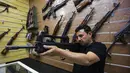 Seorang penjual, Abu Hauraa memeriksa senapan VHS buatan Kroasia di toko senjata berlisensi miliknya di Baghdad, Irak, 24 September 2018. Setelah pelegalan senjata api untuk orang sipil, permintaan akan senjata api semakin meningkat. (AFP/AHMAD AL-RUBAYE)