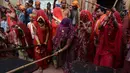 Sejumlah wanita memukul pria dengan tongkat (lathi) selama perayaan Lathmar Holi di Barsana di Mathura, India, (24/2). Lathmar Holi adalah perayaan lokal festival Hindu Holi, biasanya beberapa hari sebelum festival Holi. (AFP Photo/Dominique Faget)