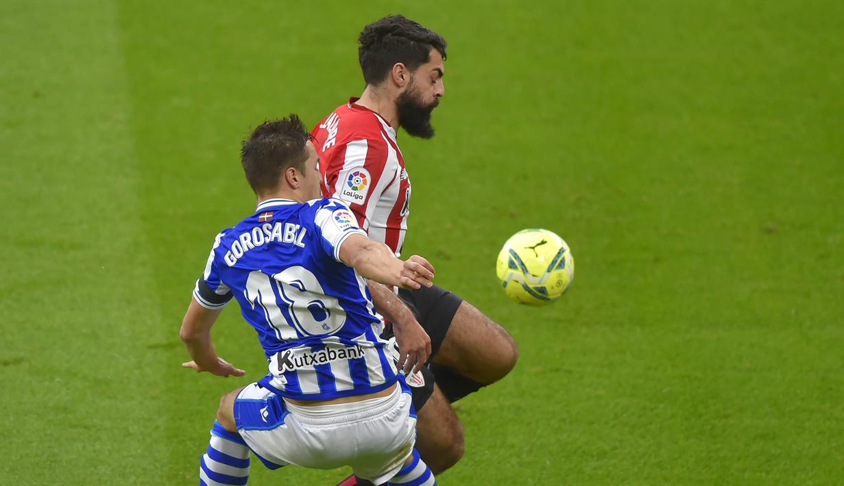 Pemain Real Sociedad, Andoni Gorosabel, berebut bola dengan pemain Athletic Bilbao, Asier Villalibre, pada laga liga Spanyol di Stadion San Mames, Kamis (31/12/2020). Real Sociedad menang dengan skor 1-0. (AFP/Ander Gillenea)
