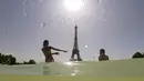 Turis dan warga menyejukkan diri dengan berendam di kolam Trocadero Fountains (air mancur Trocadero) dekat Menara Eiffel di Paris, Kamis (25/7/2019). Gelombang panas di Eropa mencapai puncaknya, bahkan suhu di ibu kota Prancis mencapai di atas 41 derajat Celcius. (Dominique FAGET / AFP)