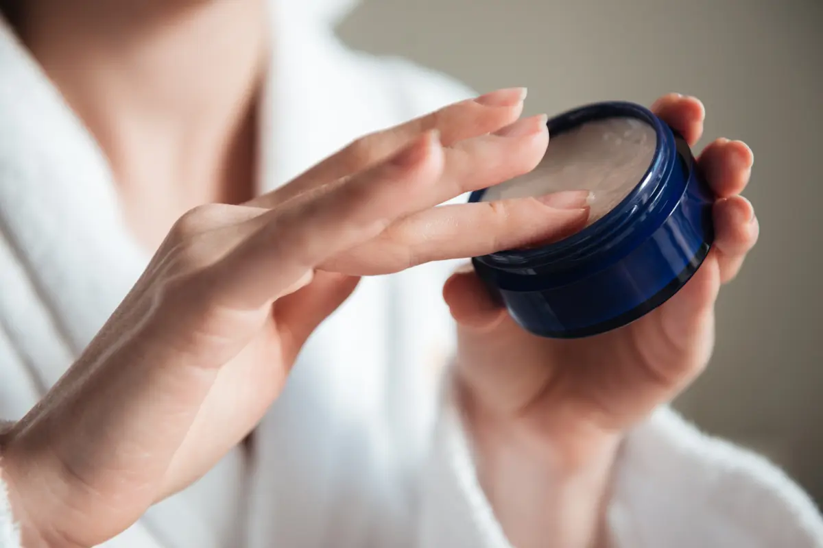 Seorang perempuan sedang mengoles parfum solid menggunakan jarinya (Foto Dok: Freepik/drobotdean)