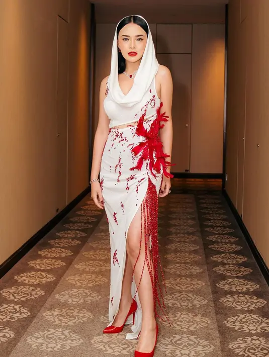 Hadiri gala premiere film Indigo,  Amanda Manopo mengenakan hooded dress putih  dengan detail 3D crystal, stone, dan feather serba merah rancangan Yenty Tan. [@bellyiverzon]