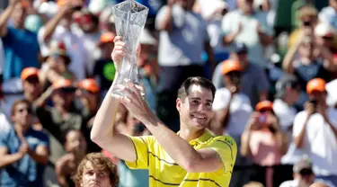 Petenis AS, John Isner memegang trofi seusai meraih gelar juara Miami Terbuka 2018 di Key Biscayne, Minggu (1/4). Pada laga final yang menegangkan tersebut, Isner sukses menaklukkan petenis Jerman Alexander Zverev 6-7, 6-4, 6-4. (AP/Lynne Sladky)