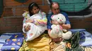 Sepasang suami istri berbaring di lantai ketika orang-orang berparade merayakan Hari Malas Sedunia di Itagui, dekat Medellin, Kolombia, Minggu (18/8/2019). (JOAQUIN SARMIENTO/AFP)