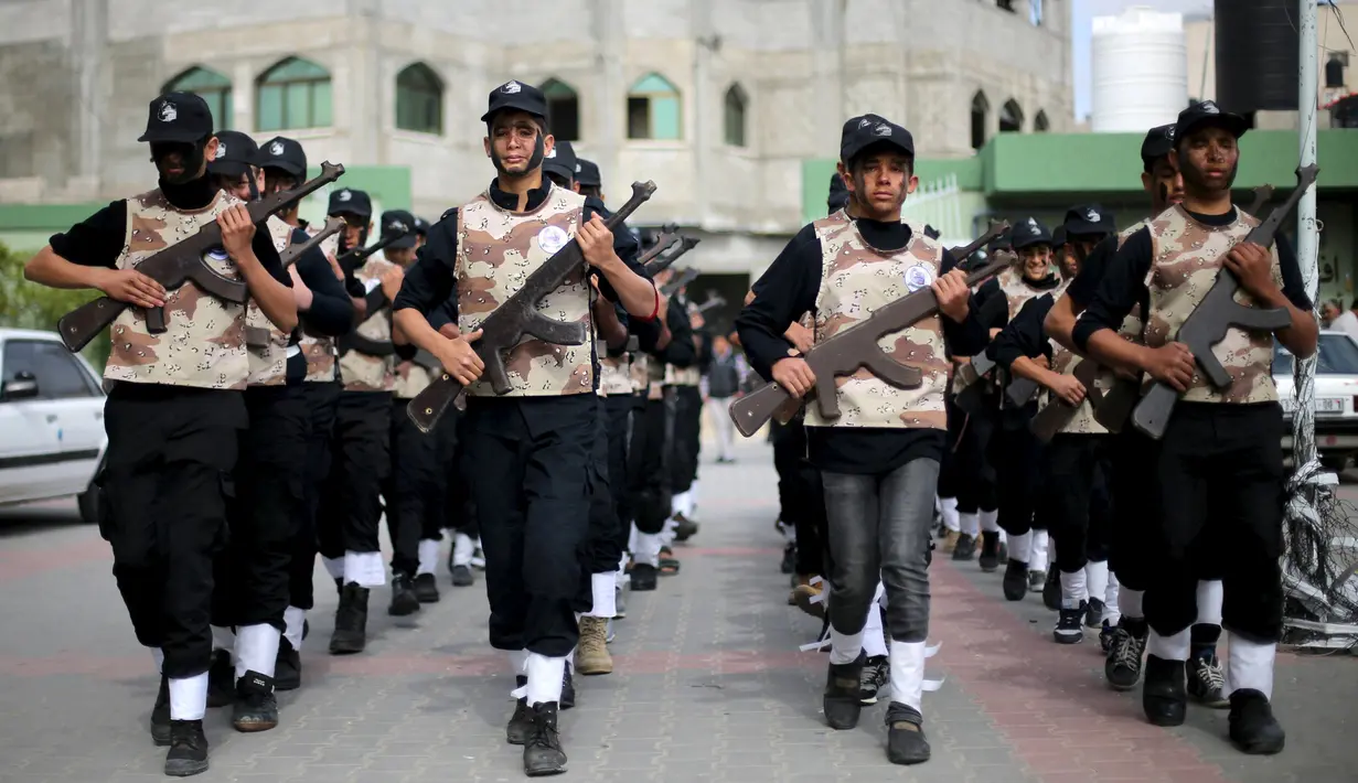 Sejumlah pelajar berbaris sambil memegang senjata kayu selama latihan militer di sebuah sekolah, Rafah, Jalur Gaza, Senin (28/3). Para pelajar dengan semangat diajarkan beberapa gerakan militer. (REUTERS / Ibraheem Abu Mustafa)