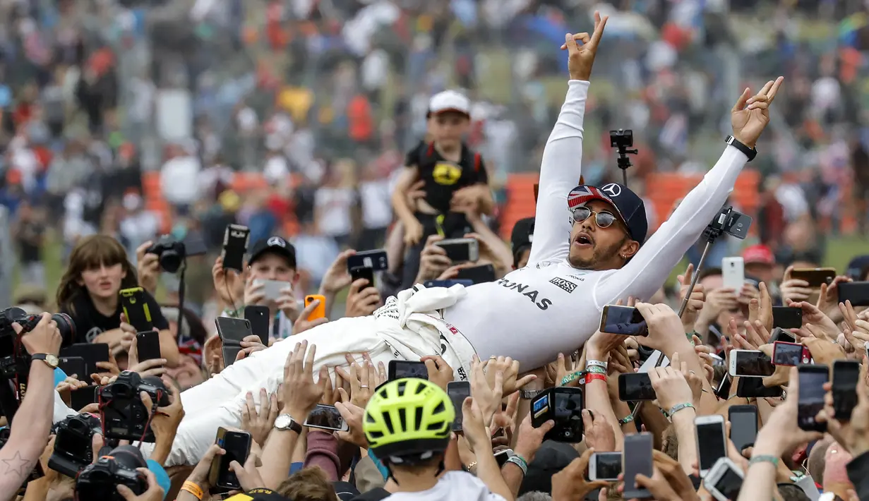 Pebalap Mercedes, Lewis Hamilton, melakukan selebrasi usai menjuarai F1 GP Inggris di Sirkuit Silverstone, Minggu (16/7/2017). Pebalap 32 tahun asal Inggris itu melahap 51 lap dengan catatan waktu 1 jam 21 menit 27,430 detik. (EPA/Valdrin Xhemaj)
