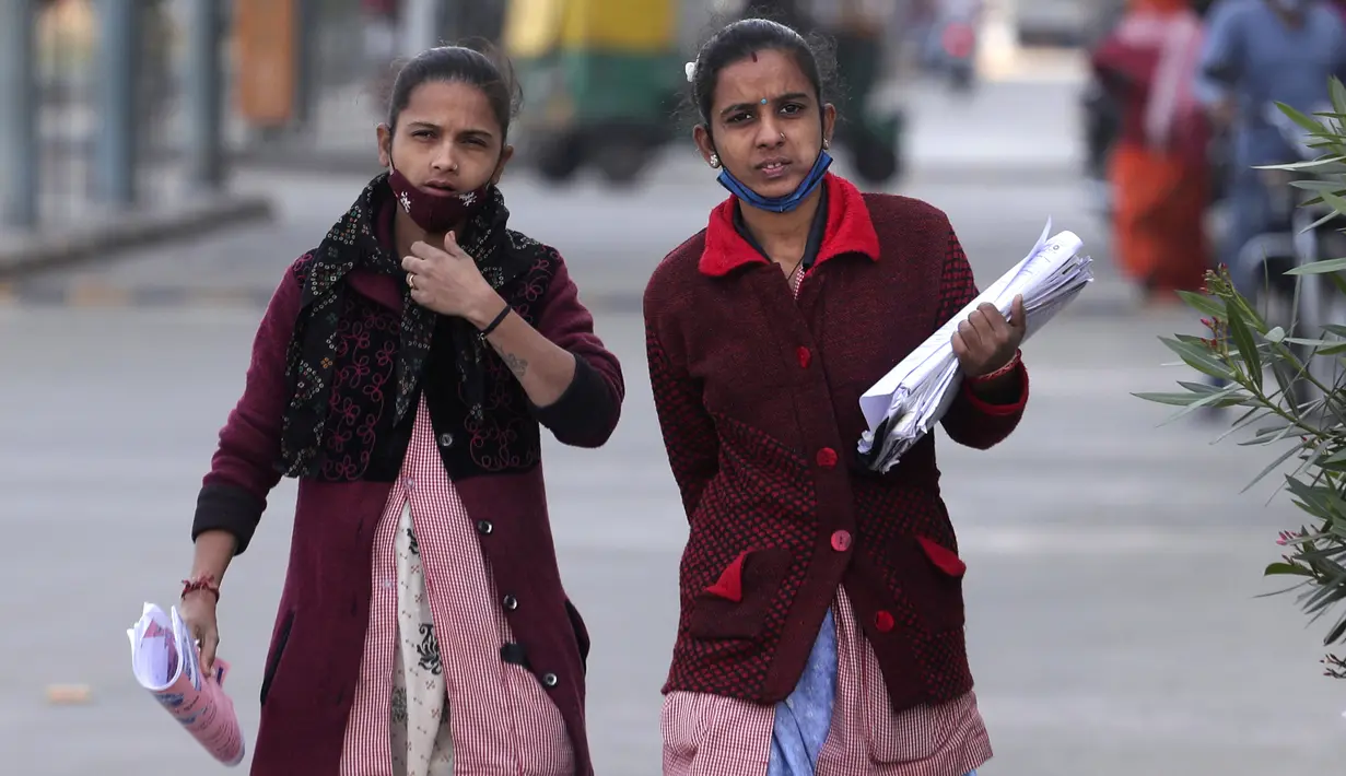 Pegawai rumah sakit berjalan dengan masker yang diletakkan di bawah hidung dan mulut di kampus rumah sakit sipil di Ahmedabad, India, Rabu, 12 Januari 2022. Di India, orang yang tertangkap tanpa memakai masker akan dedenda. (AP Photo/Ajit Solanki)