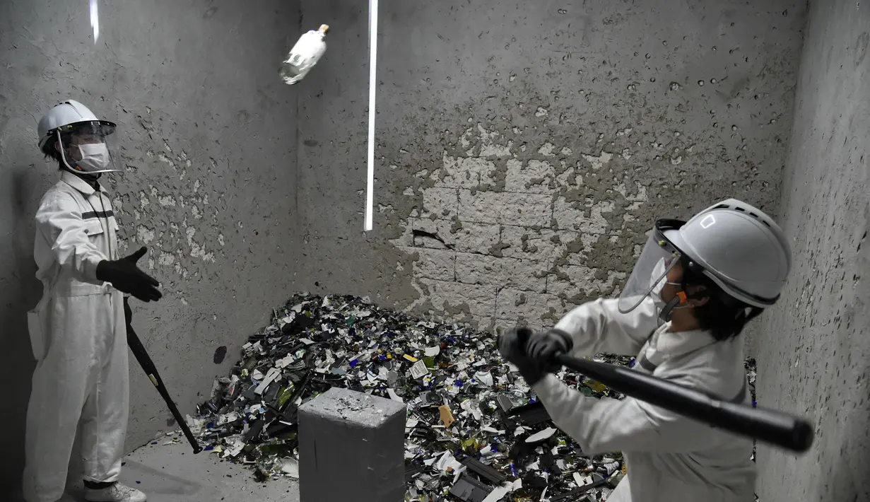 Seorang pria memukul botol yang dilempar di "rage room" atau ruang kemarahan di Singapura (19/10). Tempat ini disediakan untuk para karyawan yang ingin melampiaskan hari buruk mereka dan stres karena tekanan di kantor. (AFP Photo/Roslan Rahman)