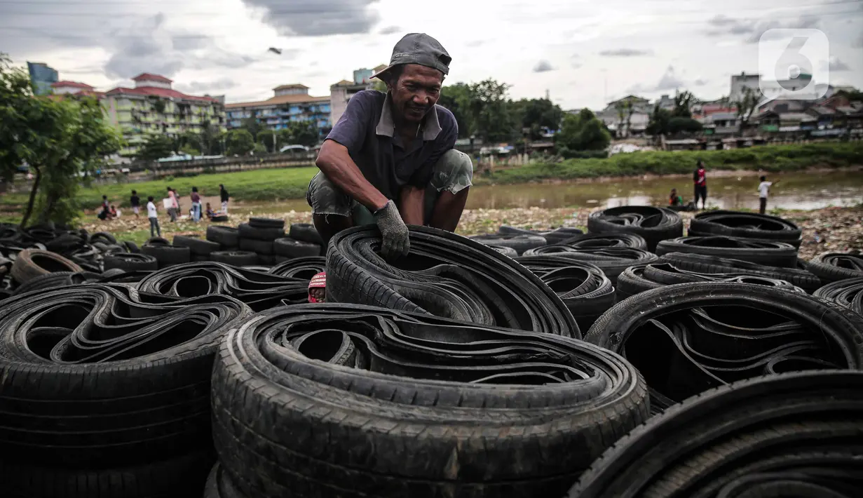 Pekerja mengumpulkan ban mobil bekas di kawasan Petamburan, Jakarta, Minggu (12/12/2021). Keterbatasan lahan membuat para pengepul terpaksa mengumpulkan limbah ban bekas dari seluruh kawasan bantaran Kanal Banjir Barat. (Liputan6.com/Faizal Fanani)