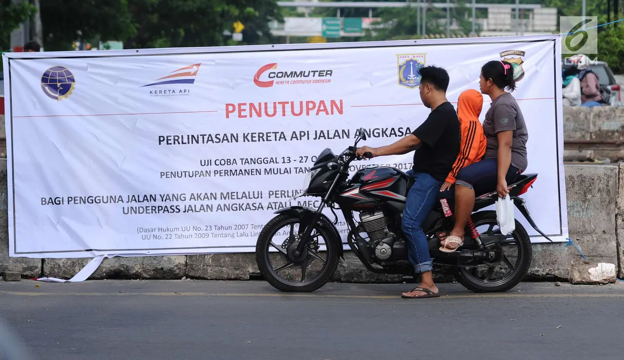 Warga membaca spanduk sosialisasi penutupan perlintasan kereta di Jalan Angkasa, Jakarta, Minggu (15/10). Penutupan secara permanen perlintasan KA di Jalan Angkasa akan dilakukan pada 3 November mendatang. (Liputan6.com/Helmi Fithriansyah)