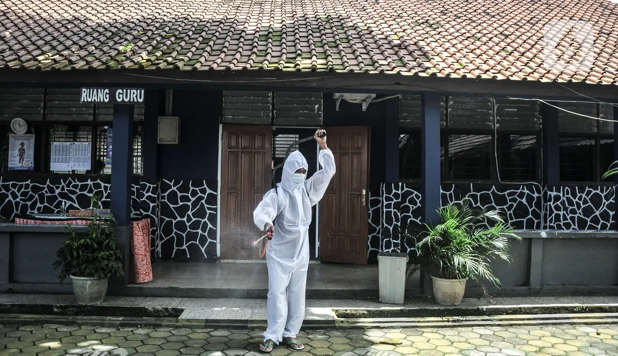 Petugas sekolah menyemprotkan disinfektan usai Pembelajaran Tatap Muka (PTM) 100 persen di SMP Negeri 9 Depok, Senin (24/1/2022). Penyemprotan disinfektan secara rutin juga dilakukan guna mengantisipasi penyebaran Covid-19 varian Omicron yang terus meningkat. (merdeka.com/Iqbal S Nugroho)