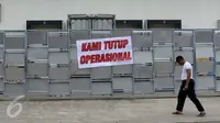Warga melewati di spanduk 'Kami Tutup Operasional' di pabrik pengolahan ikan Pelabuhan Muara Baru, Jakarta, Senin (10/10). Mogok massal karena dibatasinya masa sewa di pelabuhan selama 5 tahun yang tadinya selama 20 tahun.  (Liputan6.com/Gempur M Surya)