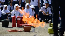 Para siswa menyaksikan petugas pemadam kebakaran memeragakan cara memadamkan api, Banda Aceh, Senin (11/11/2019). Sebanyak 439 pelajar mendapat pembekalan cara pencegahan pemadaman api akibat kebakaran dari petugas Dinas Pemadam Kebakaran dan Penyelamatan Kota Banda Aceh. (CHAIDEER MAHYUDDIN/AFP)