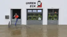 Seorang pria mencoba menumpahkan air dengan ember dari toko arlojinya di jalan dan rumah-rumah yang tergenang banjir di pusat kota Passau, Bavaria, wilayah selatan Jerman, pada 4 Juni 2024. (Michaela STACHE/AFP)