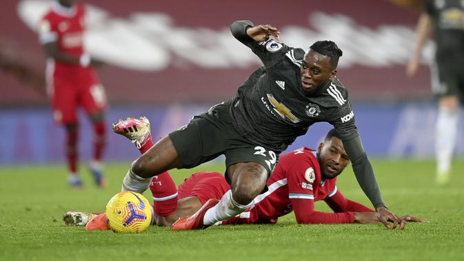 Bek Manchester United, Aaron Wan-Bissaka berebut bola dengan gelandang Liverpool, Georginio Wijnaldum pada pertandingan lanjutan Liga Inggris di Stadion Anfield, Senin (18/1/2021). Dengan hasil imbang ini, MU masih kokoh dipuncak klasemen. (Michael Regan/Pool via AP)