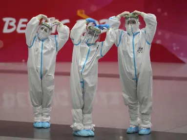 Pekerja Olimpiade dengan pakaian pelindung berpose di bandara Beijing Capital International setelah Olimpiade Musim Dingin 2022, di Beijing, China, Senin (21/2/2022). (APhoto/Frank Augstein