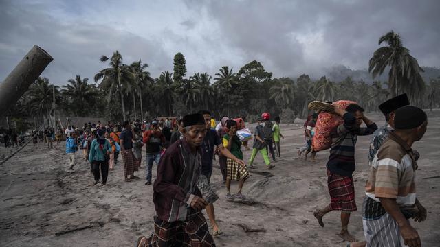 Warga menyelamatkan barang-barang mereka di daerah yang tertutup abu vulkanik setelah letusan gunung Semeru di desa Sumber Wuluh di Lumajang, Jawa Timur, Minggu (5/12/2021). BNPB menyatakan, korban meninggal akibat Gunung Semeru meletus mencapai 13 orang. (AFP /Juni Kriswanto)