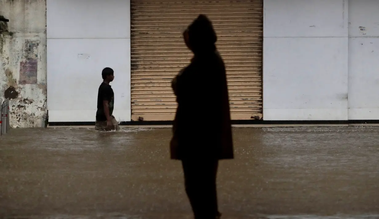 Seorang pria berjalan melintasi banjir saat hujan lebat di Mumbai, India, Rabu, (5/8/2020). Musim hujan India berlangsung dari Juni hingga September. (AP Photo/Rajanish Kakade)
