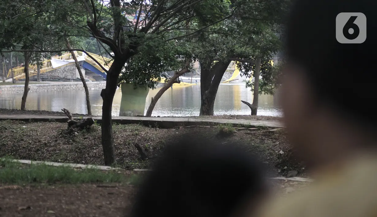 Warga melihat kondisi jembatan yang ambruk di Hutan Kota Kemayoran, Jakarta, Minggu (22/12/2019). Jembatan gantung berbentuk lengkung dan berwarna kuning tersebut ambruk sekitar pukul 13.30 WIB dan hingga kini masih diselidiki penyebab peristiwa itu. (Merdeka.com/Iqbal S. Nugroho)