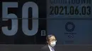 Seorang pria berjalan melewati papan hitung mundur untuk Olimpiade Tokyo 2020 50 hari sebelum upacara pembukaan, di Tokyo, Kamis (3/6/2021). (AFP/ Kazuhiro Nogi)