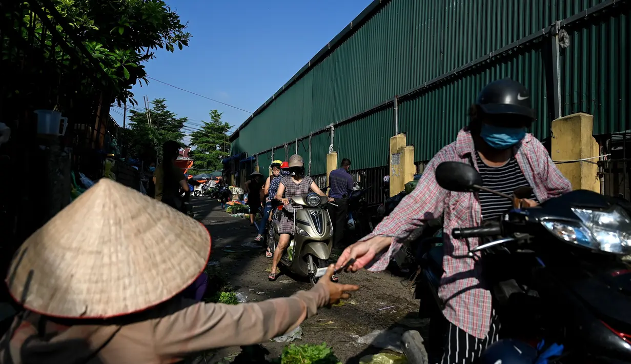 Seorang wanita membeli sayuran di pasar grosir di Hanoi (26/8/2020). (AFP Photo/Manan Vatsyayana)