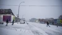 Orang-orang menyeberang jalan selama badai salju di bagian Bushwick di wilayah Brooklyn di New York, Sabtu (29/1/2022). Orang-orang dari New York City hingga Maine terbangun karena salju tebal dan angin kencang saat badai Nor'easter yang kuat melanda. (AP Photo/Brittainy Newman)