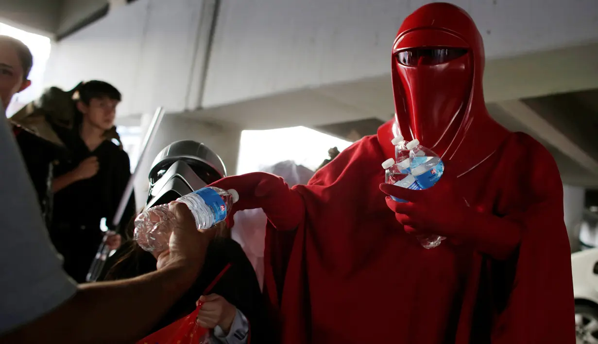 Anggota klub penggemar Star Wars, berkostum Emperor's Royal Guard, membagikan botol air ke keluarga pasien selama perayaan Star Wars Day di luar rumah sakit di Monterrey, Meksiko, Rabu (4/5).(REUTERS/Daniel Becerril)