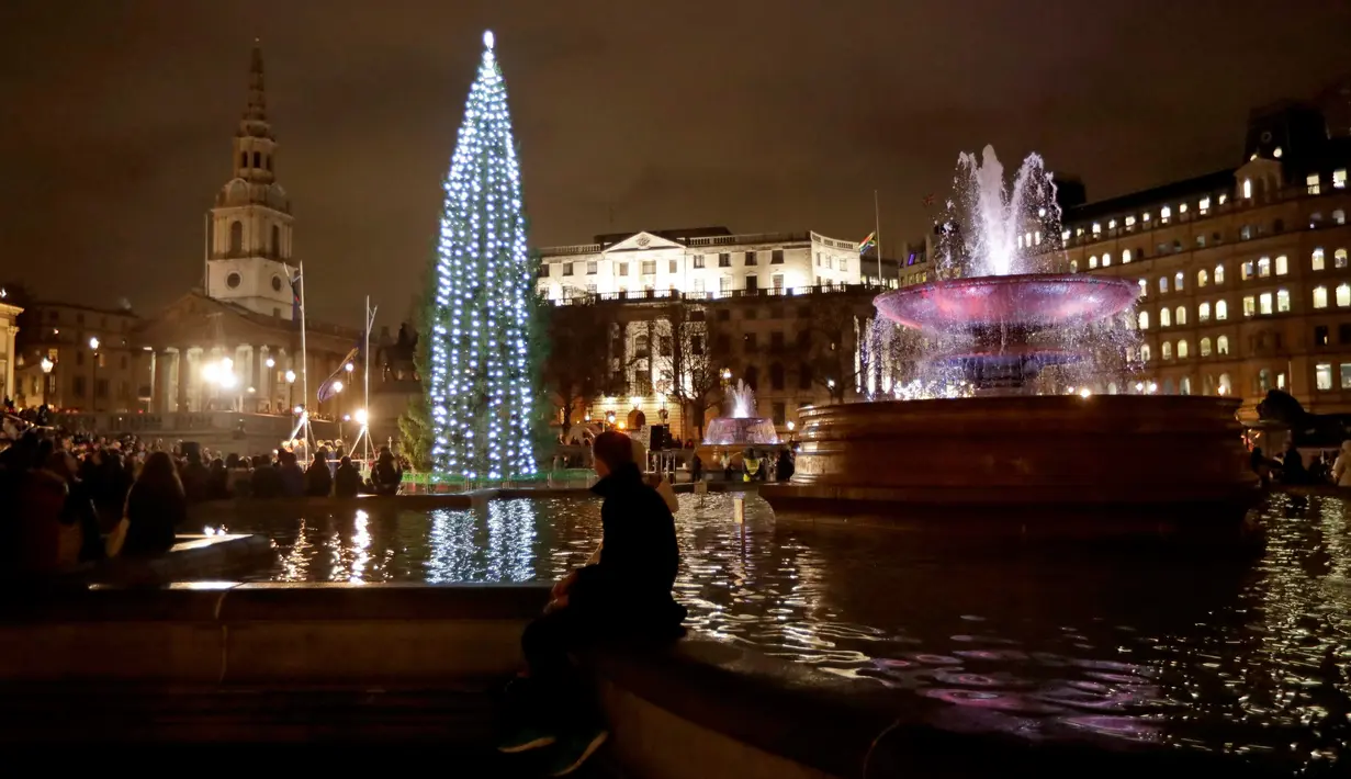 Warga duduk dekat pohon Natal setelah tradisi penyalaan lampu di Trafalgar Square, London, Kamis (6/12). Setiap tahun London mendapat pohon Natal dari Norwegia sebagai tanda terima kasih atas dukungan Inggris selama perang dunia II. (AP/Matt Dunham)