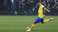 Pemain Al Nassr, Cristiano Ronaldo, menendang bola ke gawang Al Shabab dalam laga perempat final King's Cup Arab Saudi 2023 yang digelar di Al Shabab Club Stadium, Selasa (12/12/2023) dini hari WIB. (AFP/Str)