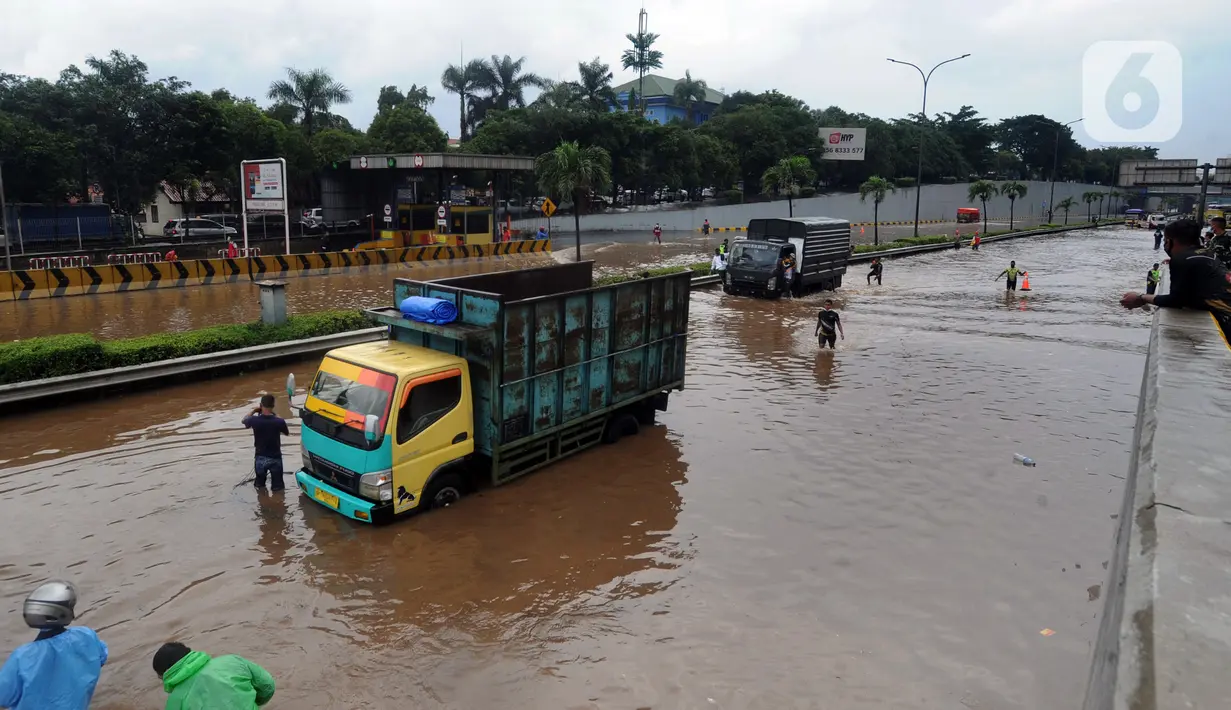 Sebuah truk mogok saat melintasi banjir yang menggenangi Jalan Tol JORR di kawasan TB Simatupang, Jakarta Selatan, Sabtu (20/2/2021). Banjir terjadi akibat luapan Kali Serua yang berada di pinggir jalan tol. (merdeka.com/Arie Basuki)