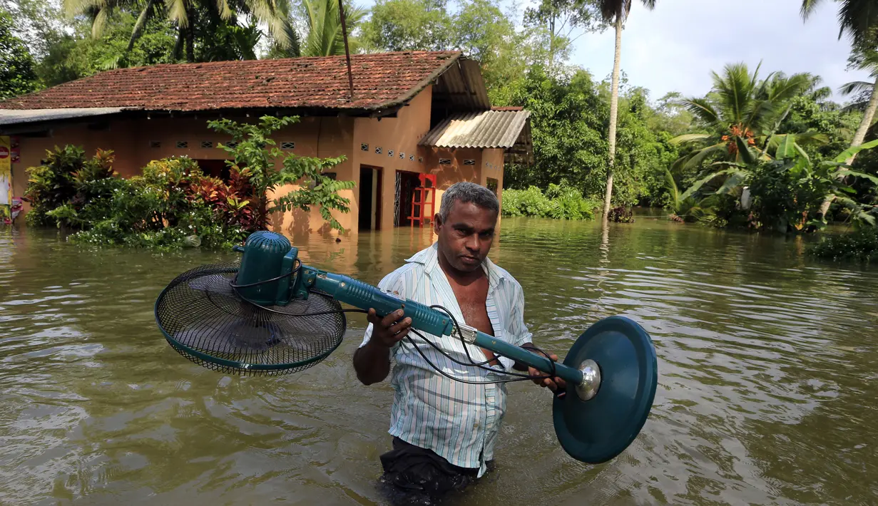Seorang warga menyelamatkan barang-barangnya dari banjir di Sri Lanka, Minggu (28/5). Atas bencana banjir dan longsor ini, Kementerian Luar Negeri Sri Lanka telah mengajukan permintaan bantuan dari PBB dan negara-negara tetangga. (AP Photo)