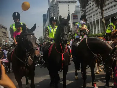 Sejumlah anak berfoto dengan polisi berkuda dari Direktorat Polisi Satwa Mabes Polri di kawasan Bundaran HI, Jakarta, Minggu (17/11/2019). Polisi berkuda tersebut khusus ditugaskan mengawasi keamanan CFD serta memperkenalkan kepada warga. (Liputan6.com/Faizal Fanani)