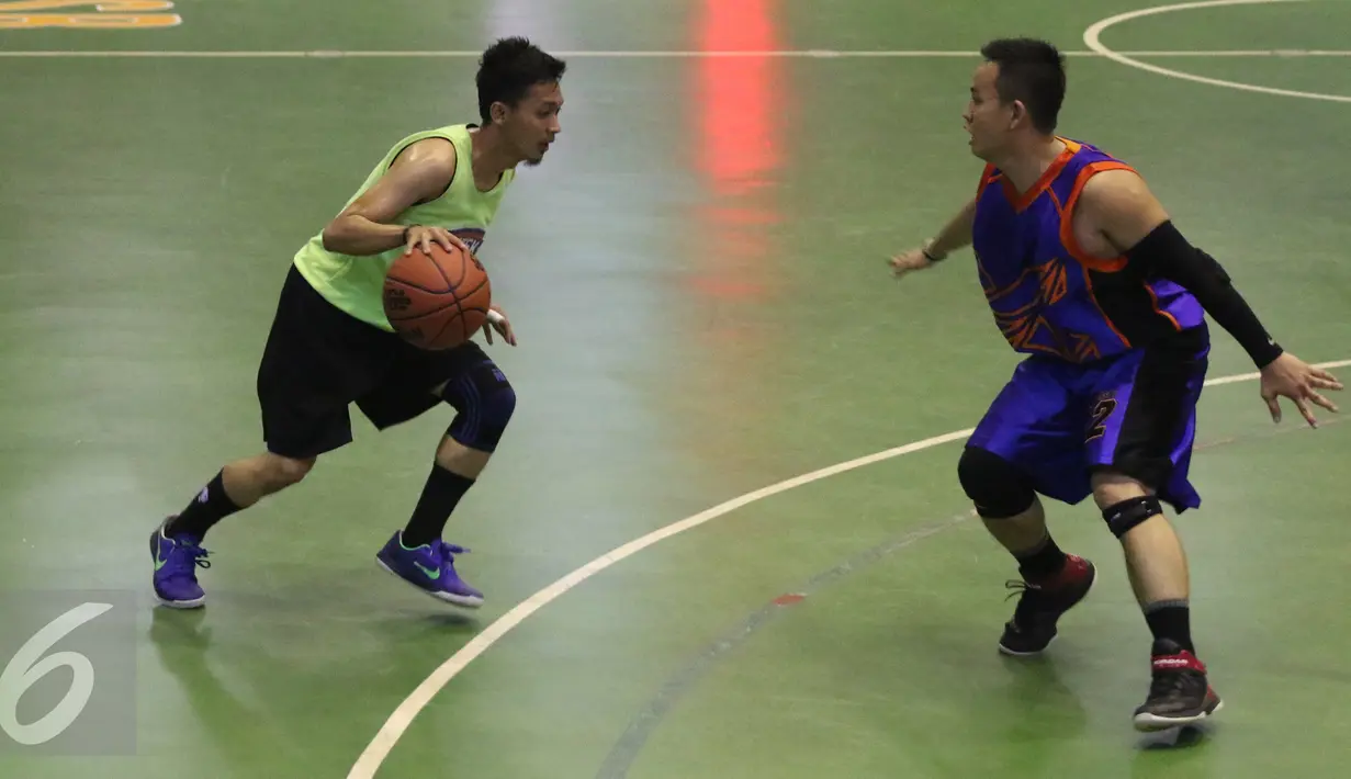 Pemain no 12 dari SCTV Emtek, Adit berusaha melewati pemain dari kompas tv pada saat  laga final Invitasi Bola Basket Antarmedia Nasional (IBBAMNAS) 2016 di GOR Mahasiswa Sumantri Brodjonegoro, Jakarta, Sabtu (16/4/2016). (Liputan6.com/Herman Zakharia)
