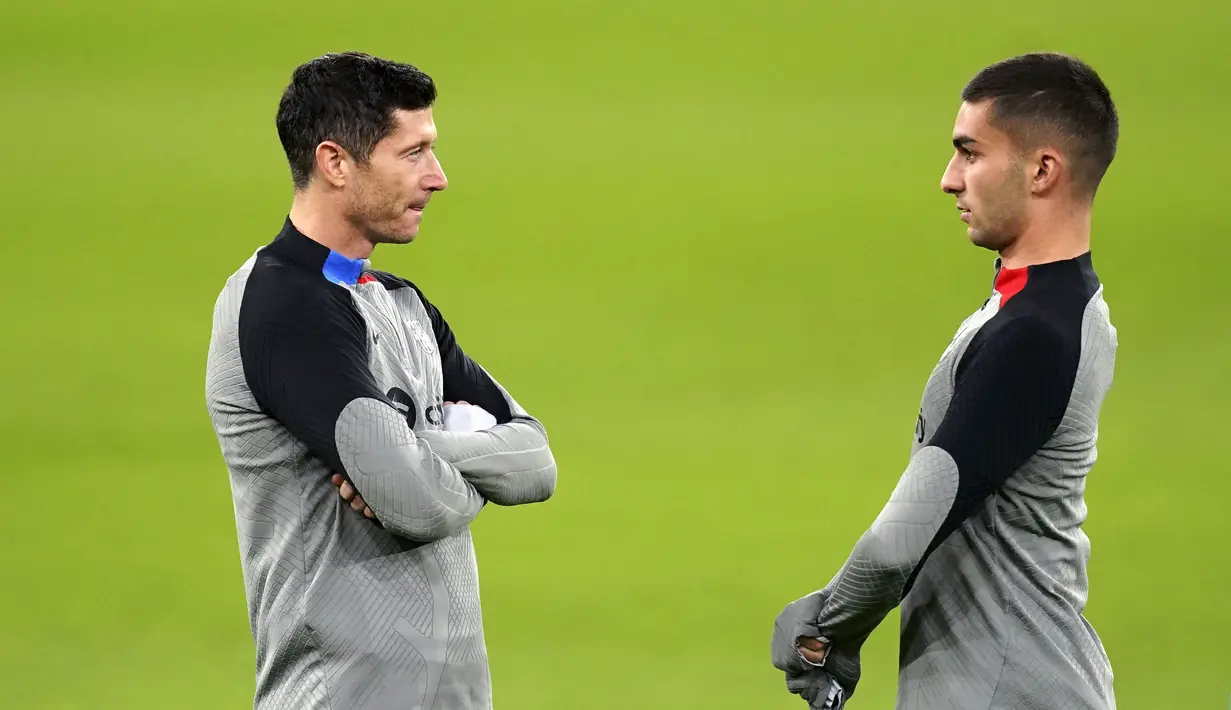 Penyerang Barcelona, Ferran Torres (kanan) dan Robert Lewandowski berdiri di lapangan selama sesi latihan jelang lawan Manchester United di Old Trafford, Manchester, Inggris, Rabu 22 Februari 2023. Barcelona harus kehilangan dua pemain muda andalannya, yakni Pedri dan Gavi. Nama keduanya tak masuk dalam skuad yang disiapkan xavi. (Martin Rickett/PA via AP)