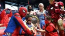 Dua orang berkostum superhero berpose dengan seorang anak yang menerima vaksin Covid-19 Pfizer-BioNtech untuk anak-anak berusia 5-11 di sebuah gym di San Juan City, pinggiran kota Manila, Filipina pada 7 Februari 2022. (Ted ALJIBE / AFP)