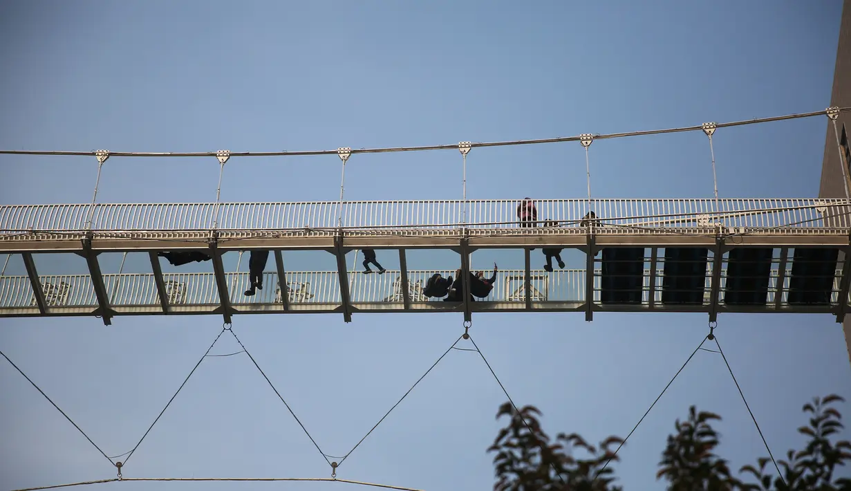 Sejumlah orang melintasi jembatan kaca di Shijiazhuang, Provinsi Hebei, China, Sabtu (24/11). Jembatan ini memiliki panjang 100 meter. (AFP)