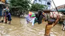 Pedagang penjual alat kebersihan melewati banjir untuk masuk ke kompleks Pondok Gede Permai, Jatiasih, Bekasi, Jumat (22/4). Mereka menjajakan dagangannya berupa alat kebersihan ketika banjir di  kawasan tersebut mulai surut. (Liputan6.com/Fery Pradolo)