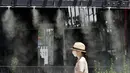 Seorang wanita berjalan di bawah titik kabut yang menyejukkan di sepanjang jalan di Tokyo, Selasa (10/8/2021). Menurut biro meteorologi Jepang, cuaca panas panas terus berlanjut di wilayah metropolitan saat suhu naik menjadi 338 derajat Celcius (100,4 derajat Fahrenheit). (AP Photo/Eugene Hoshiko)