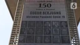 Videotron penghormatan kepada tenaga medis yang gugur akibat Covid-19 terpasang pada tiang penyangga lintasan MRT, Jalan Sisingamangaraja, Jakarta, Jumat (18/9/2020). Masyarakat diharapkan selalu menjaga protokol kesehatan saat berada di luar ruangan. (Liputan6.com/Herman Zakharia)