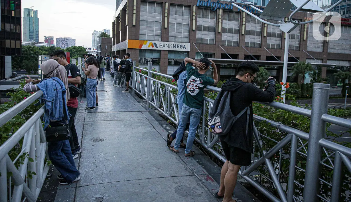 Warga berkumpul diatas JPO tanpa atap di Jakarta, Minggu (12/9/2021). Kasus baru positif Covid-19 di Indonesia per Minggu (12/9) bertambah sebanyak 3.779 kasus Jumlah tersebut membuat total kasus virus corona sejak awal pandemi mencapai 4.167.511 kasus. (Liputan6.com/Faizal Fanani)