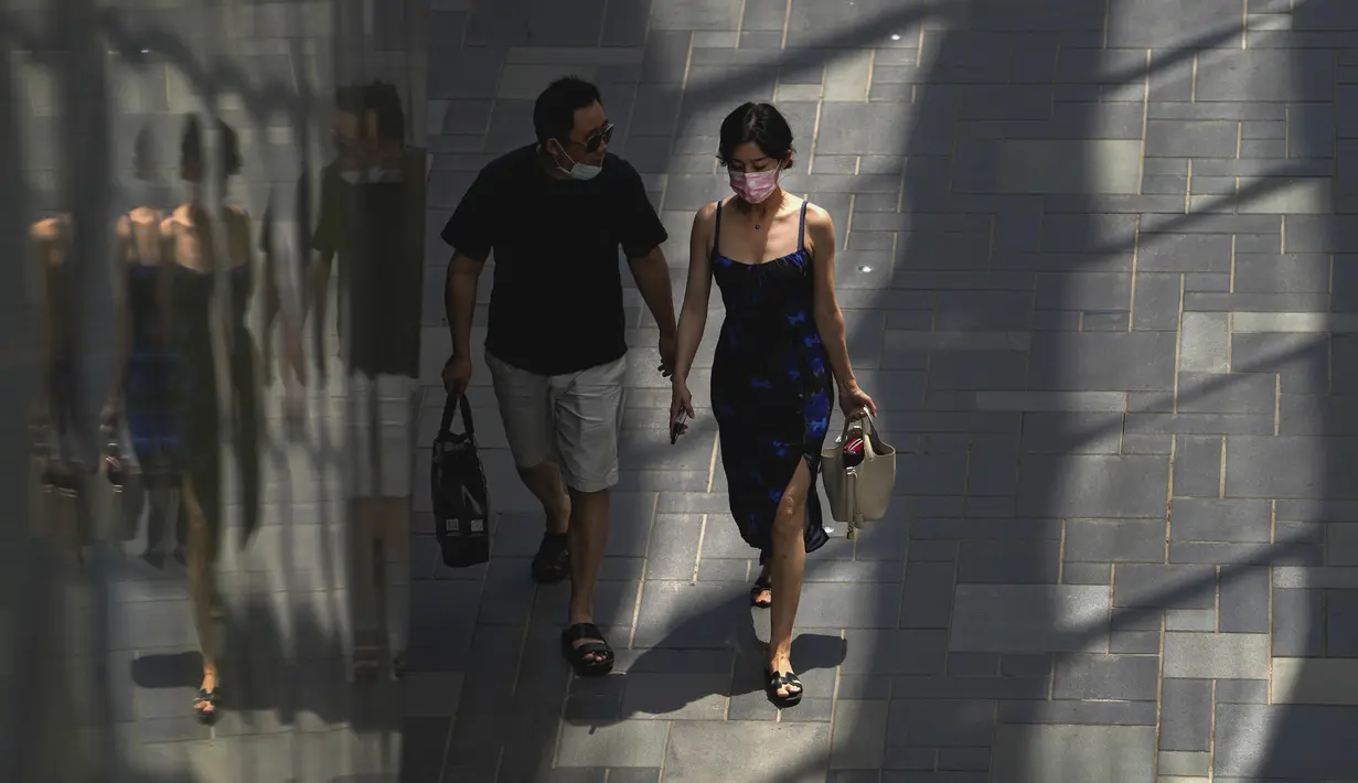 Sepasang kekasih yang mengenakan masker berjalan melalui pusat perbelanjaan di Beijing, Senin (6/6/2022). Pengunjung kembali ke restoran di sebagian besar Beijing untuk pertama kalinya dalam lebih dari sebulan sebagai pihak berwenang lebih lanjut melonggarkan pembatasan terkait pandemi wabah COVID-19. (AP Photo/Andy Wong)