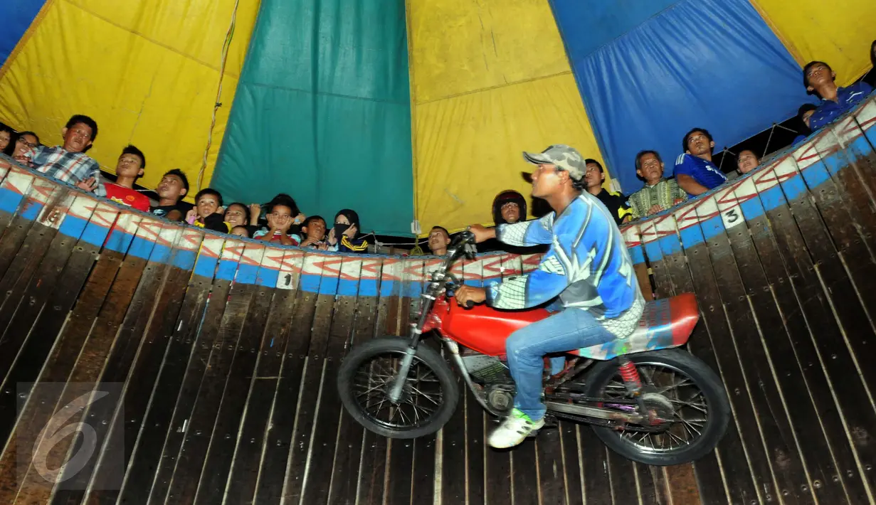 Pengendara motor melakukan akrobat 'Tong setan' di pasar malam PURI BETA II, Tangerang , Banten, Kamis (31/12). Acara ini untuk menghibur masyarakat yang ingin menghabiskan malam tahun baru. (Liputan6.com/Helmi Afandi)