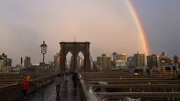 Warga beraktivitas saat pelangi terlihat dari Jembatan Brooklyn di New York City, AS (15/5). Jembatan ini selesai dibangun 1883 dan menghubungkan borough Manhattan dan Brooklyn di New York City melintasi Sungai East. (AFP Photo/Hector Retamal)