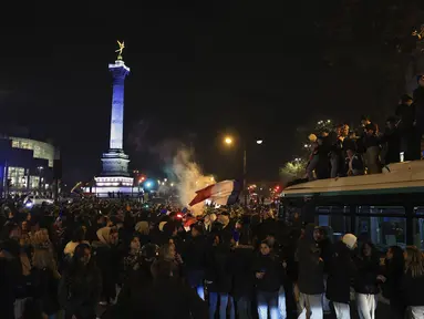 Suporter Prancis bergembira di alun-alun Bastille usai kemenangan pertandingan semifinal Piala Dunia 2022 melawan Maroko, di Paris, Kamis (15/12/2022). Prancis berhasil mengalahkan Maroko dengan skor 2-0 dan melaju ke babak final menghadapi Argentina. (AP Photo/Aurelien Morissard)