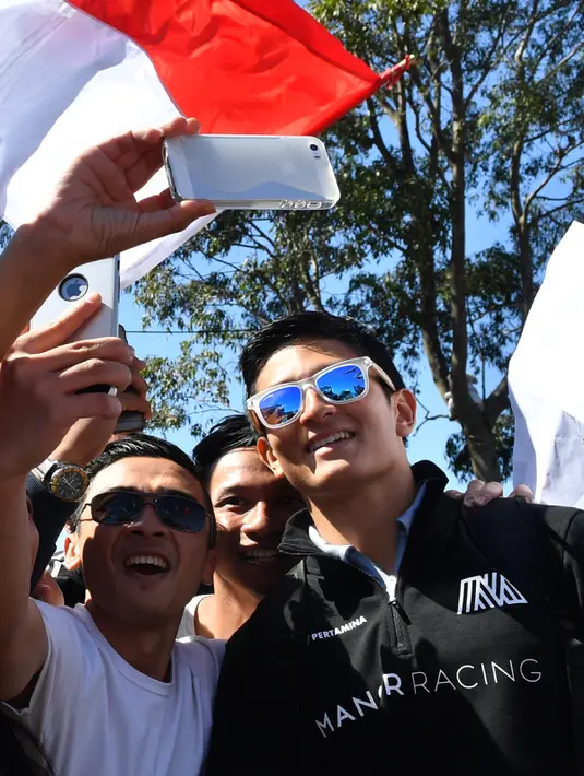 Pembalap Manor Racing, Rio Haryanto berselfie dengan penggemarnya menjelang debut pada ajang Formula 1 di GP Australia, Melbourne, Minggu (20/3). Akibat mendapat hukuman, Rio Haryanto harus memulai Grand Prix Australia dari posisi buncit. (Paul Crock/AFP)